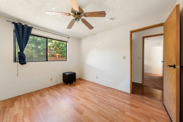 empty room featuring a textured ceiling, light hardwood / wood-style flooring, and ceiling fan