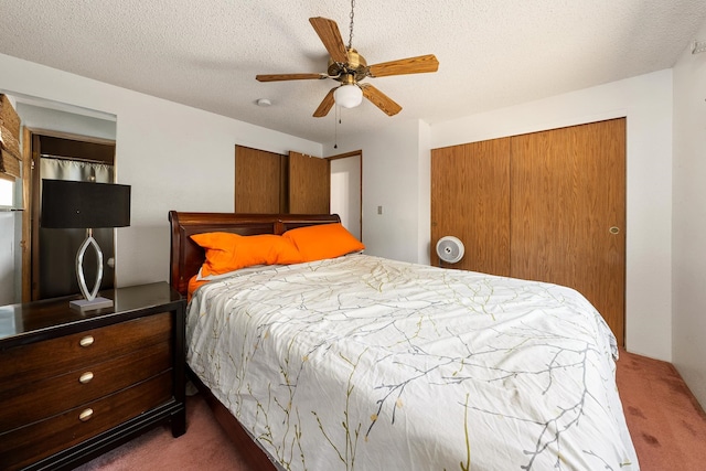 bedroom with ceiling fan, dark carpet, a textured ceiling, and a closet