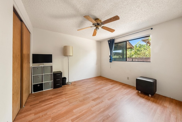 interior space featuring ceiling fan, light wood-type flooring, and a textured ceiling