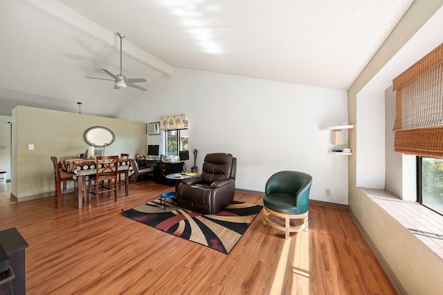 living room featuring ceiling fan, beam ceiling, light hardwood / wood-style floors, and a healthy amount of sunlight