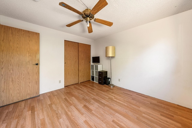 unfurnished bedroom with ceiling fan, light hardwood / wood-style flooring, a textured ceiling, and a closet