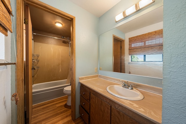 full bathroom featuring toilet, hardwood / wood-style floors, washtub / shower combination, and vanity