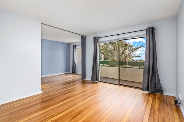 spare room with a textured ceiling and light hardwood / wood-style flooring