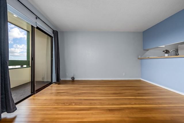 empty room with light wood-type flooring and a textured ceiling