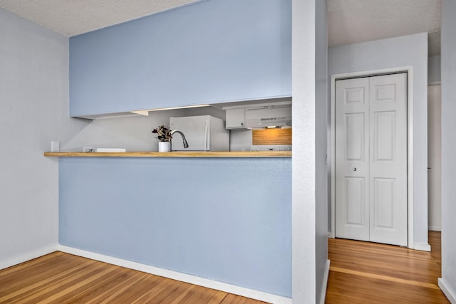 kitchen with kitchen peninsula, light hardwood / wood-style flooring, a textured ceiling, and white refrigerator