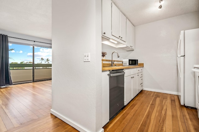 kitchen featuring white refrigerator, white cabinets, stainless steel dishwasher, and light hardwood / wood-style floors