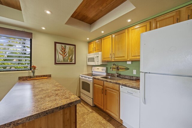 kitchen featuring white appliances, sink, and a tray ceiling