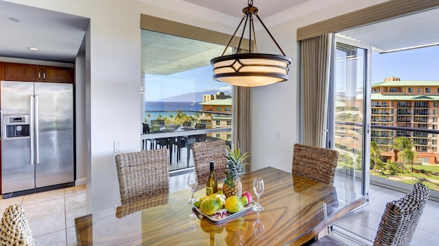 dining room with crown molding, light tile patterned floors, a wall of windows, and a water view