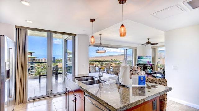 kitchen with a wealth of natural light, pendant lighting, stainless steel appliances, an island with sink, and sink