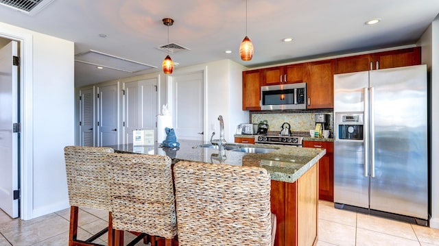 kitchen with light tile patterned floors, a kitchen island with sink, appliances with stainless steel finishes, and sink