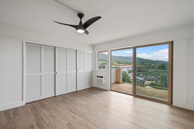 2158 Main St Unit 704, Wailuku, HI 96793 - unfurnished bedroom with access to exterior, wood finished floors, a wall mounted AC, and ceiling fan