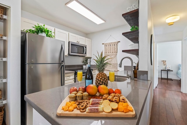 480 Kenolio Rd Unit 13-101, Kihei, HI 96753 - kitchen with stainless steel appliances, a sink, white cabinetry, open shelves, and hardwood / wood-style floors