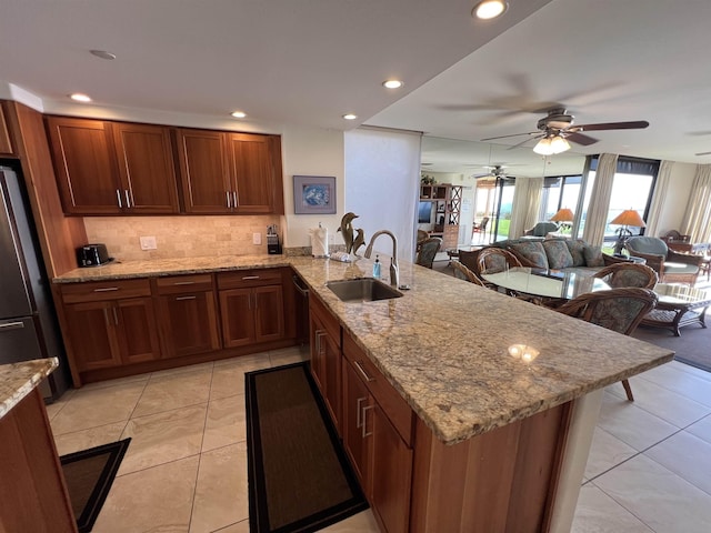 kitchen with a sink, light tile patterned floors, ceiling fan, a peninsula, and appliances with stainless steel finishes