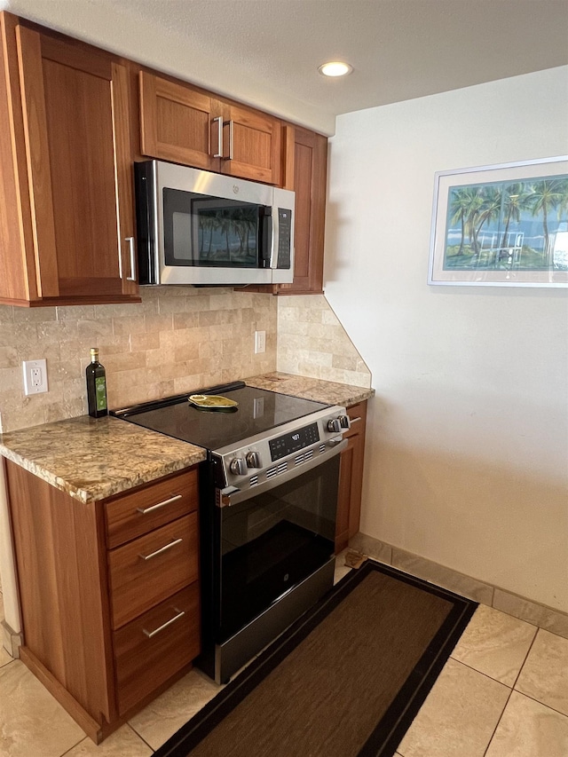 kitchen featuring recessed lighting, brown cabinets, decorative backsplash, light tile patterned flooring, and appliances with stainless steel finishes