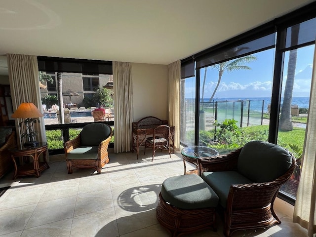 sunroom featuring a water view, a wall of windows, and tile patterned floors