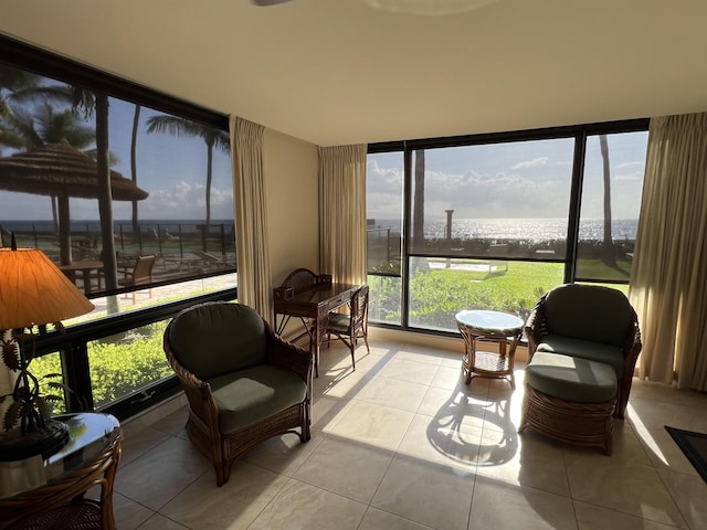 sunroom / solarium with a water view, a wall of windows, and tile patterned floors