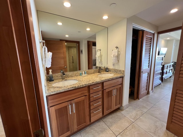 full bath featuring tile patterned floors, recessed lighting, double vanity, and a sink