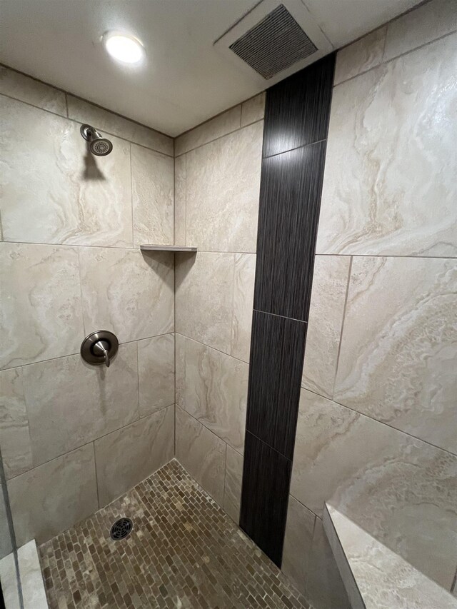 bathroom with a tile shower and visible vents