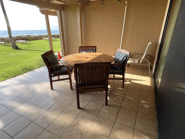 exterior space featuring a textured wall, tile patterned flooring, and a water view