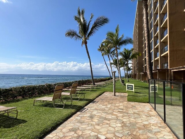 surrounding community with a water view and a lawn