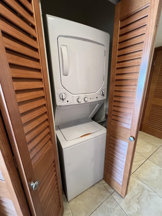 laundry area with light tile patterned floors, stacked washer / drying machine, and laundry area
