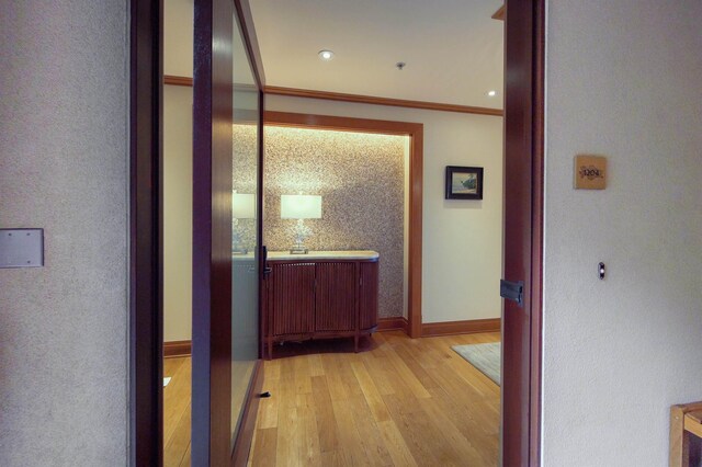 hall with light hardwood / wood-style floors and crown molding