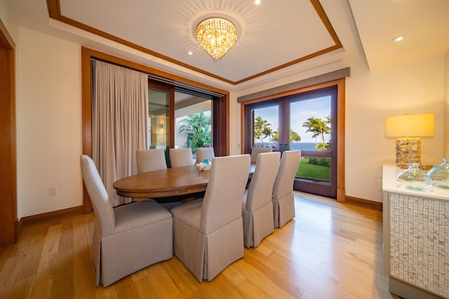 dining room featuring ornamental molding, light hardwood / wood-style floors, a notable chandelier, and french doors