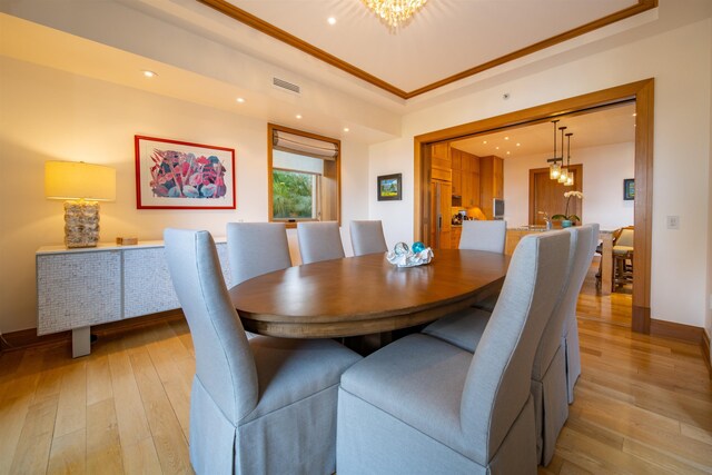 dining room featuring ornamental molding, light hardwood / wood-style flooring, and an inviting chandelier