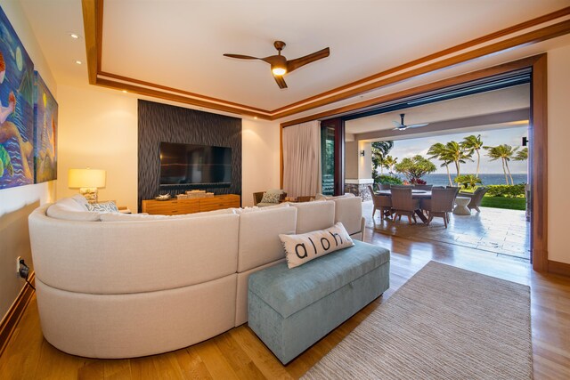 living room featuring crown molding, wood-type flooring, and ceiling fan