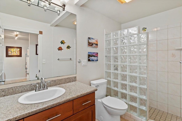 bathroom with a tile shower, vanity, and toilet