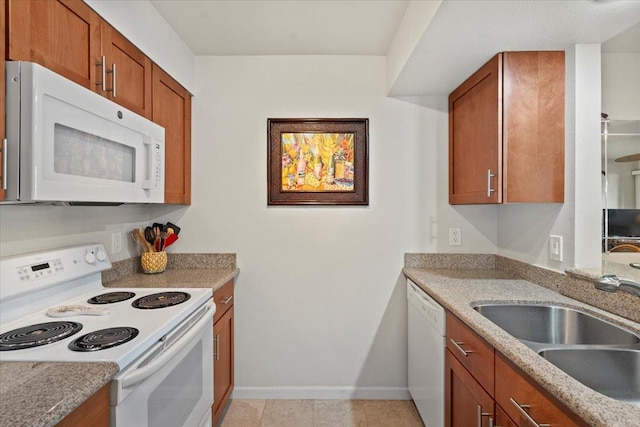 kitchen featuring light stone countertops, sink, light tile patterned floors, and white appliances