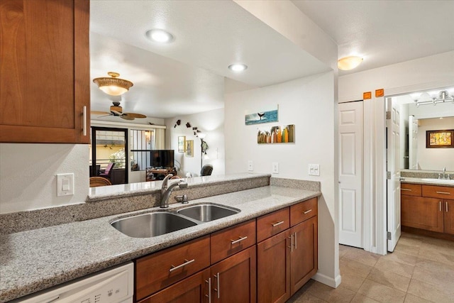 kitchen with ceiling fan, sink, dishwasher, and light stone counters