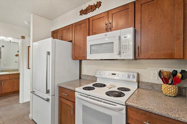 kitchen featuring light stone countertops, white appliances, sink, and light tile patterned floors