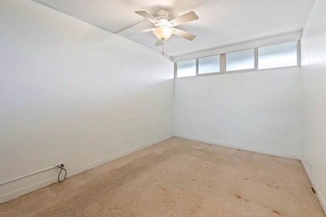 spare room featuring light carpet, ceiling fan, and baseboards