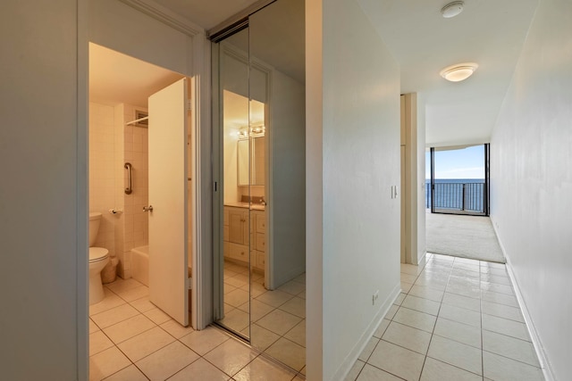 corridor featuring baseboards and light tile patterned floors