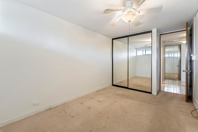 unfurnished bedroom featuring carpet floors, a ceiling fan, baseboards, and a closet