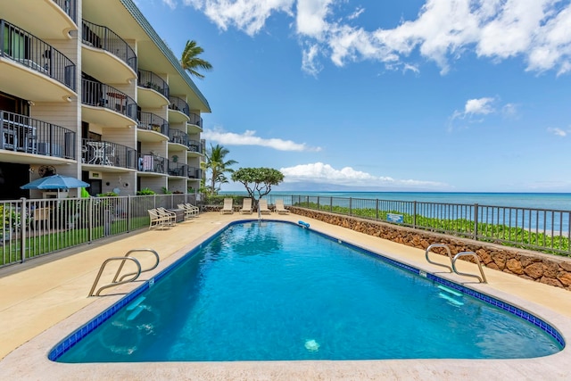 pool featuring a water view, fence, and a patio