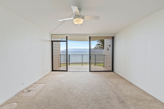 empty room featuring expansive windows, ceiling fan, carpet flooring, and baseboards