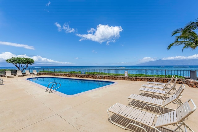 pool with a water view, fence, and a patio