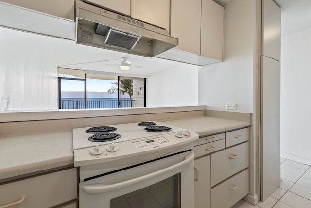 kitchen featuring light tile patterned floors, a ceiling fan, light countertops, white electric range, and under cabinet range hood