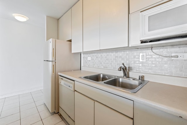 kitchen featuring white appliances, tasteful backsplash, light countertops, a sink, and light tile patterned flooring