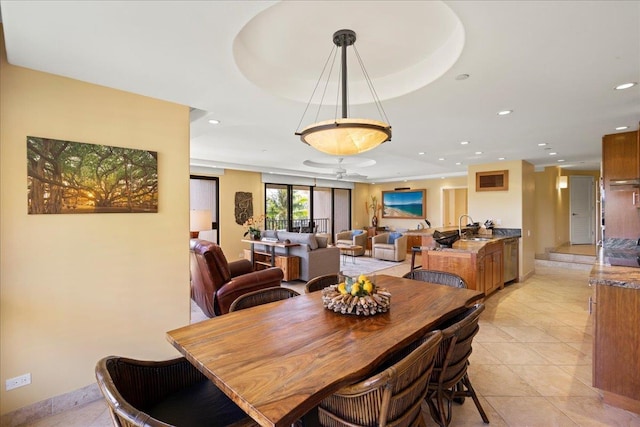 tiled dining area featuring a raised ceiling, ceiling fan, and sink