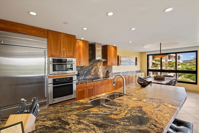 kitchen with sink, wall chimney exhaust hood, hanging light fixtures, stainless steel appliances, and light tile patterned floors