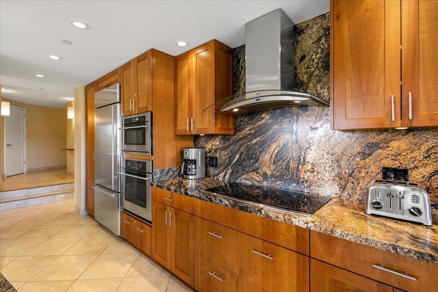 kitchen featuring black stovetop, wall chimney exhaust hood, dark stone countertops, light tile patterned floors, and tasteful backsplash