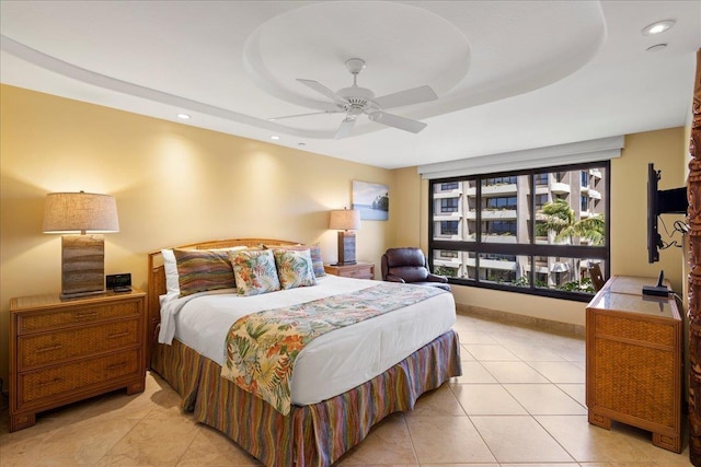 bedroom with a tray ceiling, ceiling fan, and light tile patterned flooring