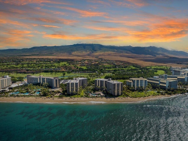 aerial view at dusk with a mountain view and a view of the beach