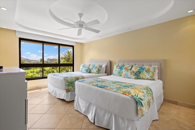 bedroom featuring a tray ceiling, ceiling fan, and light tile patterned floors