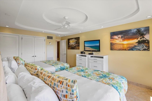 bedroom featuring ceiling fan, a raised ceiling, and light tile patterned floors