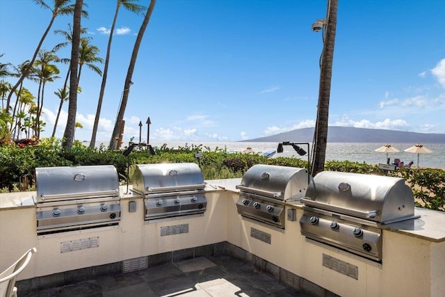 view of patio / terrace featuring an outdoor kitchen, a water and mountain view, and a grill