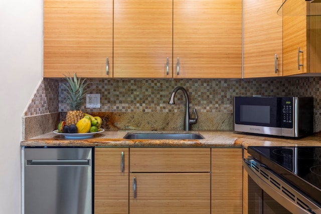 kitchen with appliances with stainless steel finishes, stone countertops, tasteful backsplash, and sink